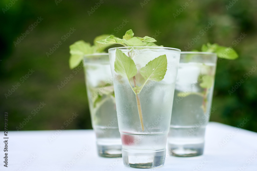 Summer hot fresh drink with mint in glass on white green grey background Summer hot fresh drink with mint in glass on white green grey background