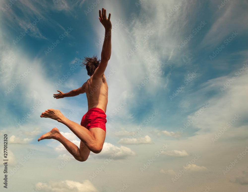 Fototapeta premium Man jumping over cloudly sky background. Summer fun lifestyle