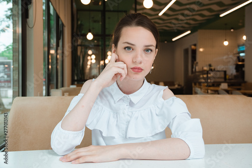 girl on white blouse sits in cafe and waits