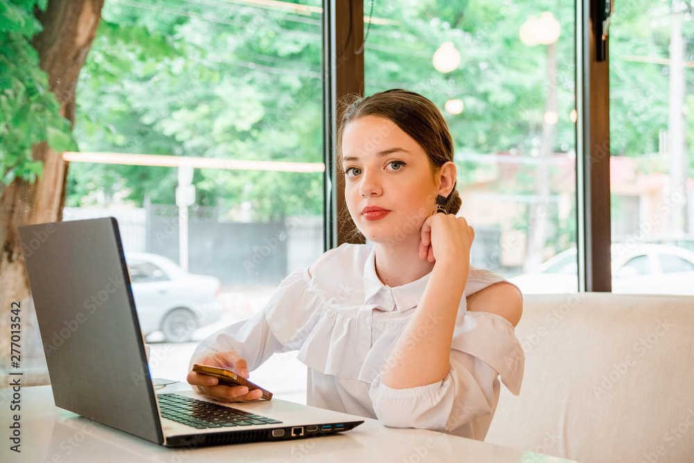 girl in cafe at lunch works behind a laptop