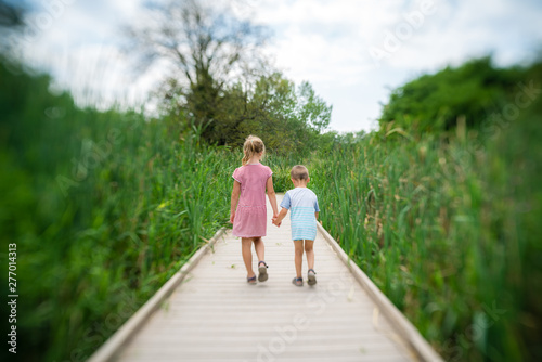 Obraz na płótnie Brother and sister walking on the wooden platform w salonie