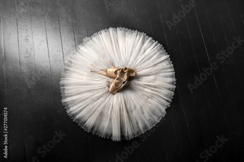 Pointe shoes. Peach shoes, ballet shoes with ribbons on a white tutu in a dance studio. Advertising ballet school. Professional ballerina outfit.