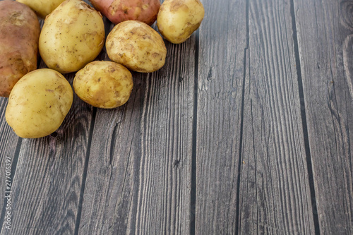 Young raw unpeeled potatoes on wooden dark background. Harvest. Flat lay composition. Layout with copy space for text .