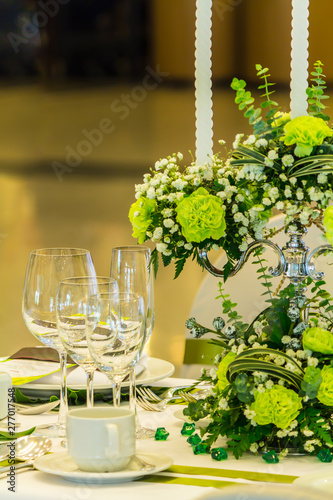 Wedding party dinner table setting with tableware and silverware and glasses set and Candlestick and flower in restaurant.