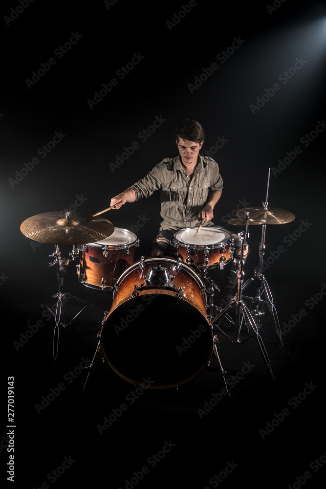 Fototapeta premium Professional drummer playing on drum set on stage on the black background