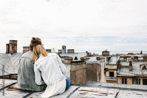 A young couple sits on the roof and admires a beautiful view of the city. Romance, love and trusting relationships. Or he dream or digital detox together.
