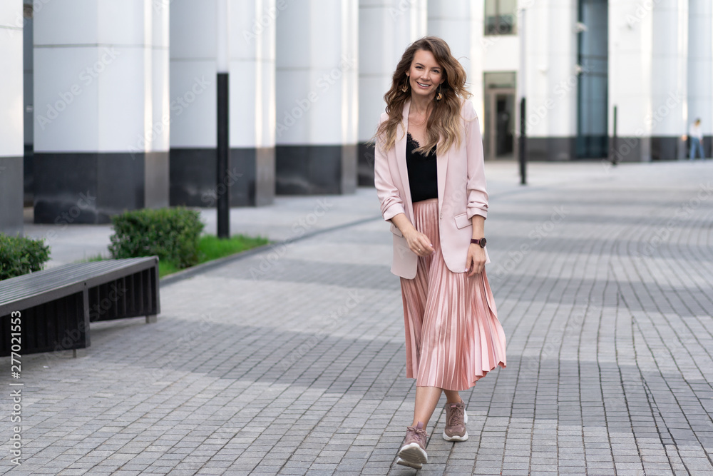 young light-skinned relaxed girl in fashionable clothes walks along the street with a great mood. Lifestyle