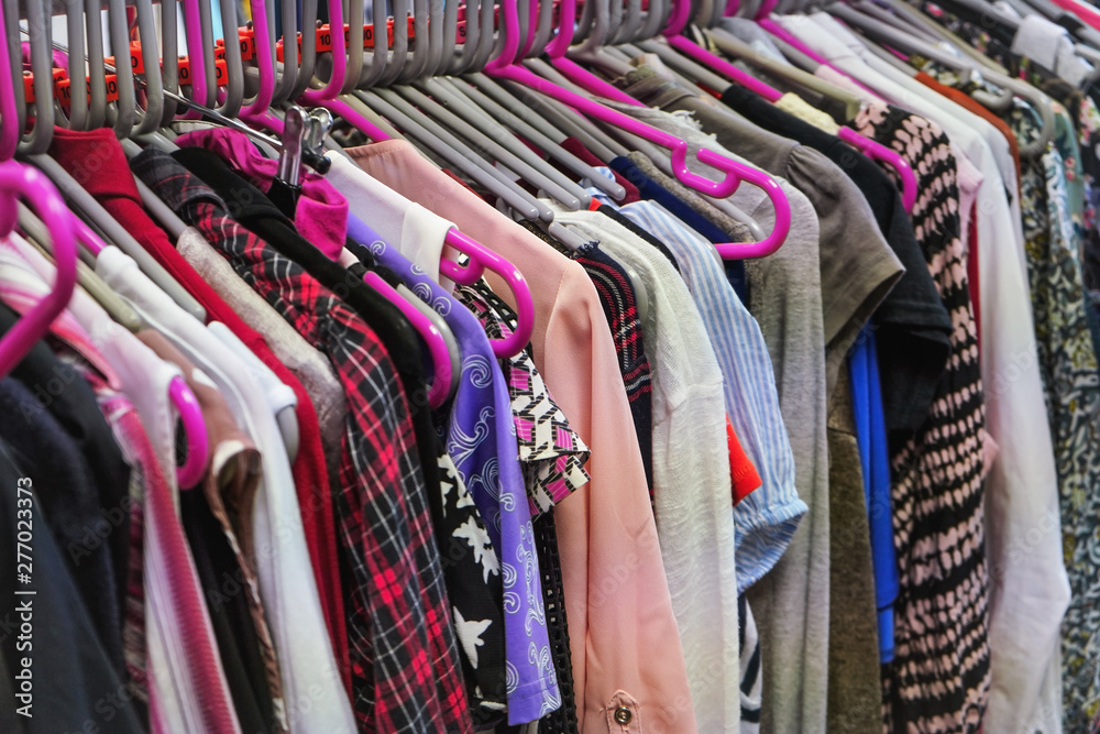 Various women clothing on mostly pink coat hangers inside charity second  hand thrift shop Stock Photo | Adobe Stock