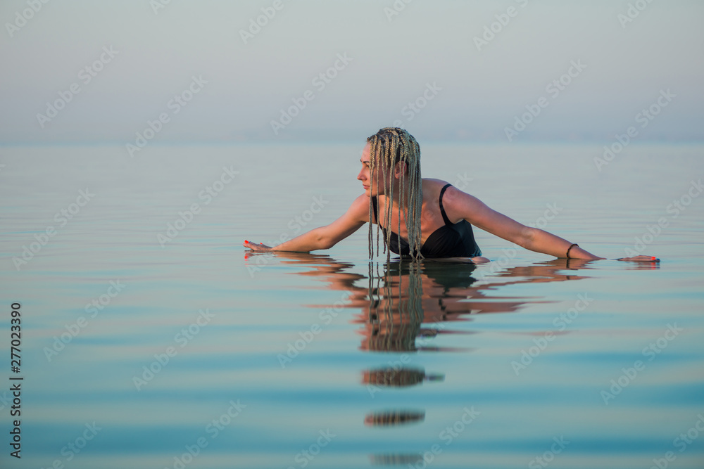 young woman in swim suit enjoy calm sea water at summer sunset