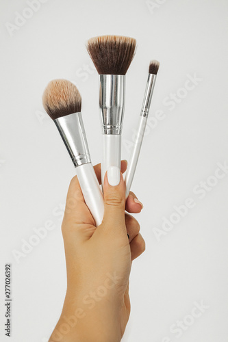 Makeup brushes in hand on white background