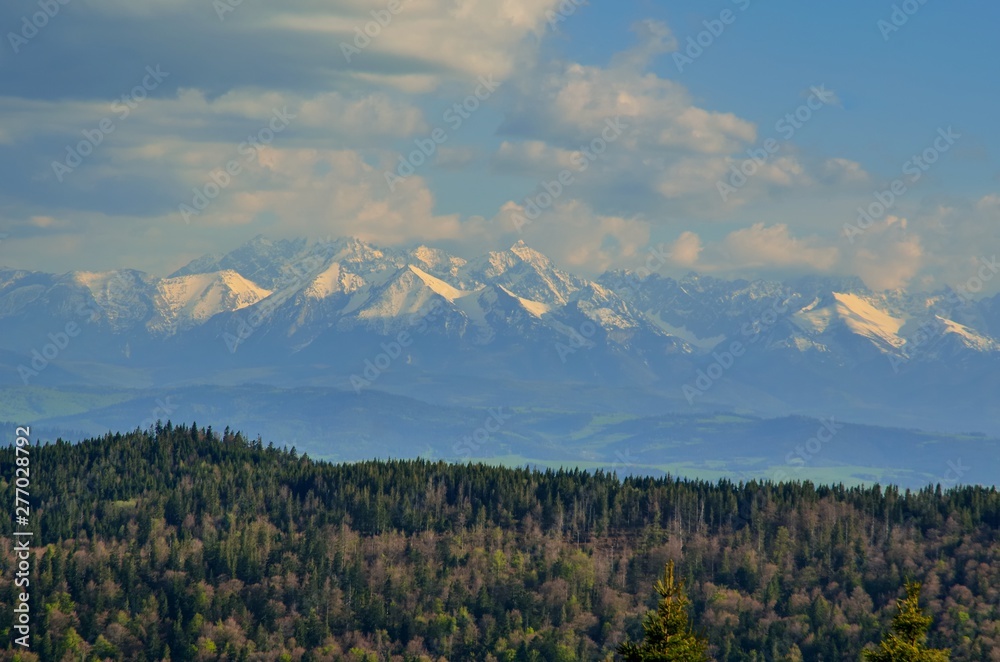Charming spring mountain landscape. Beautifully snow-covered high peaks over hills.