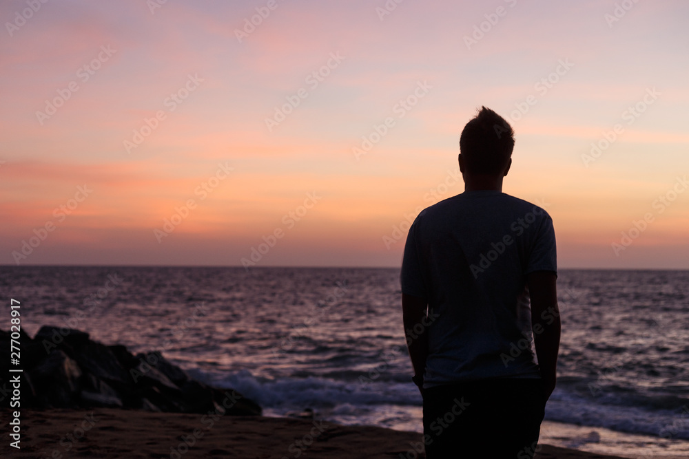 Silhouette of a man against the ocean at sunset