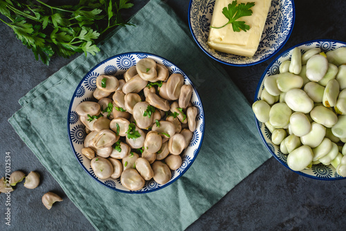 Boiled broad beans served in a bowl with butter and parsley photo