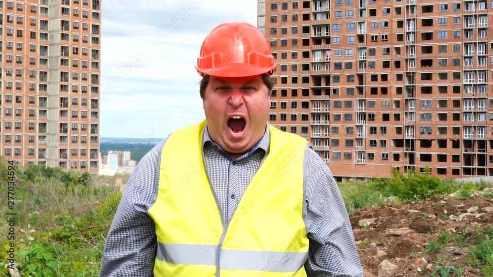 Male builder foreman, worker or architect on construction building site is shouting and looking to camera