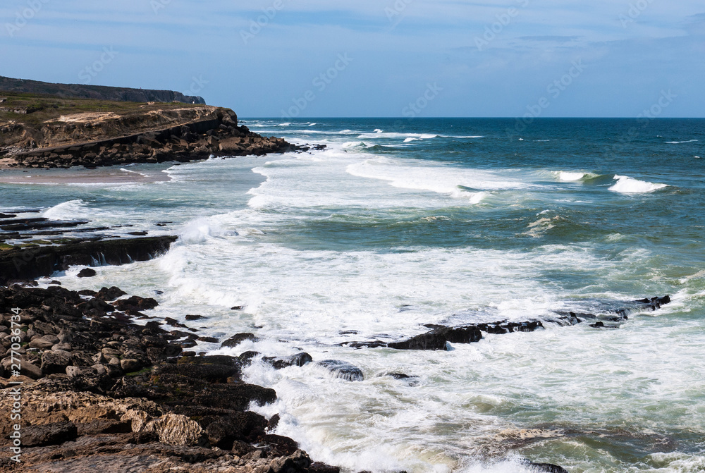 Praia das Maçãs in Portugal - view of a beautiful beach and rocky coastline with large waves on a sunny summer day