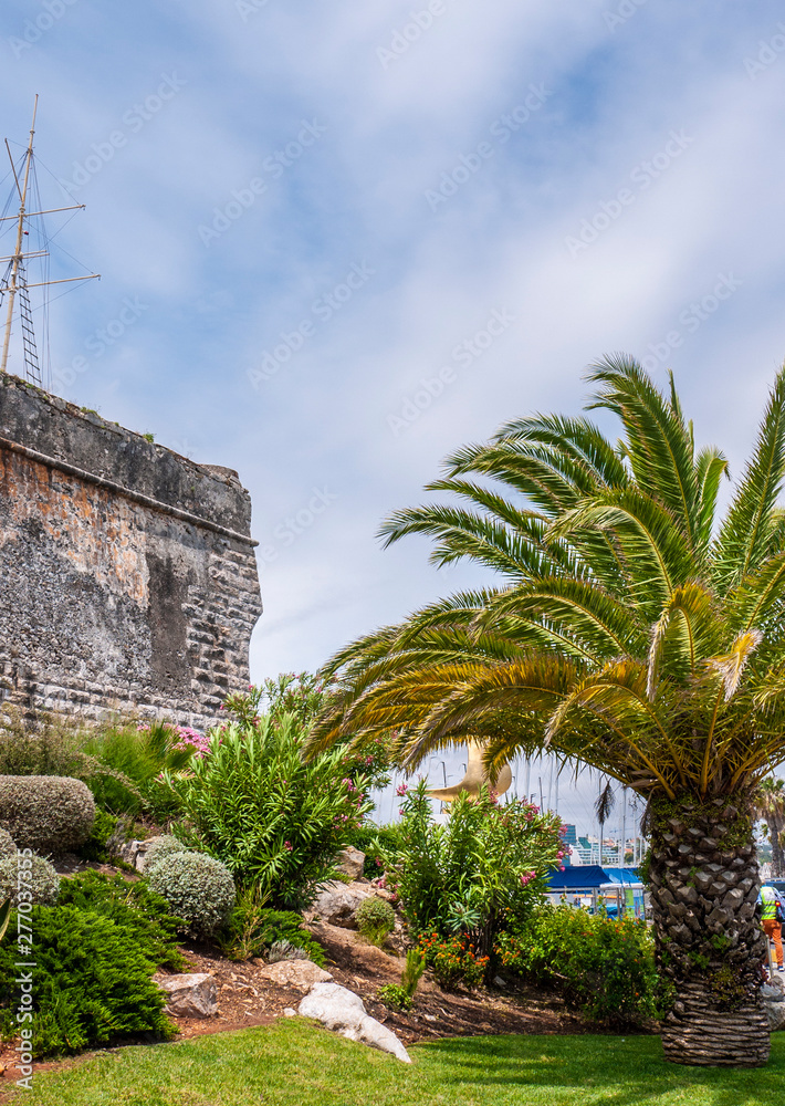 Old stone walls of the Citadel of Cascais, Portugal with beautiful gardens, taken on a cloudy summer day