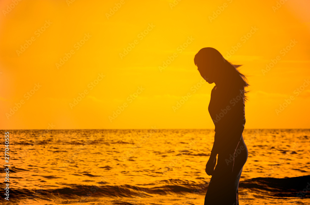 beautiful young slim girl standing on sandy beach.