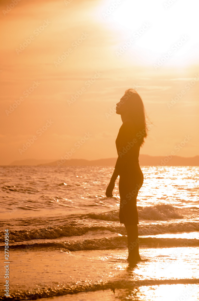 beautiful young slim girl standing on sandy beach.