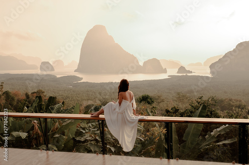 Woman with the white dress sit and see the mountain in early morning at the Sametnangshe Island viewpoint, Phang-Nga, Thailand. photo