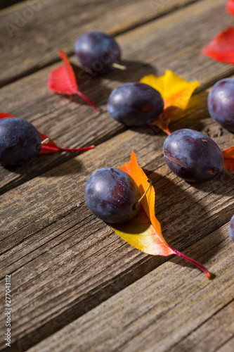 plums and color autumn leaves on old wood table