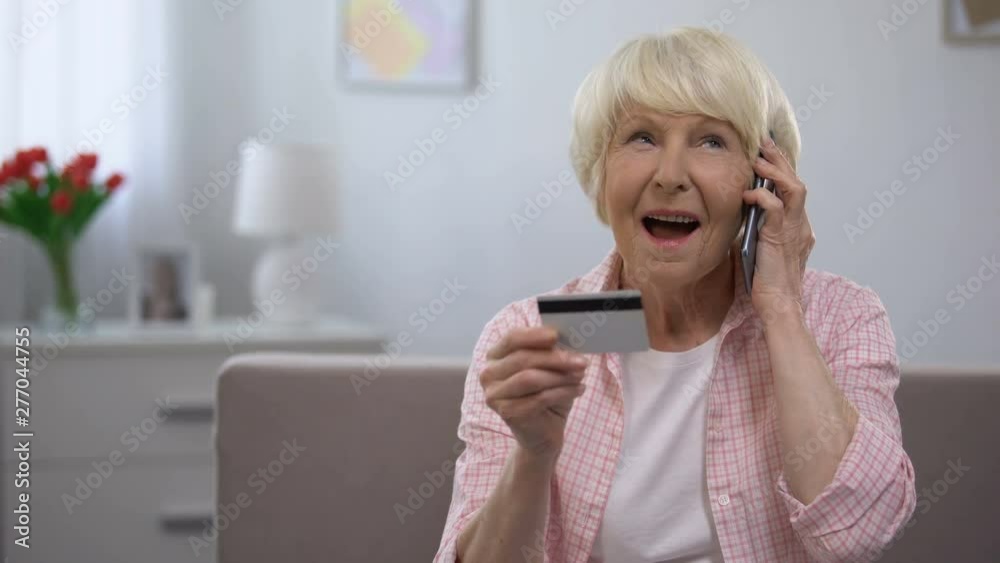 Old woman holding credit card and talking phone, banking programs for old people Old woman holding credit card and talking phone, banking programs for old people