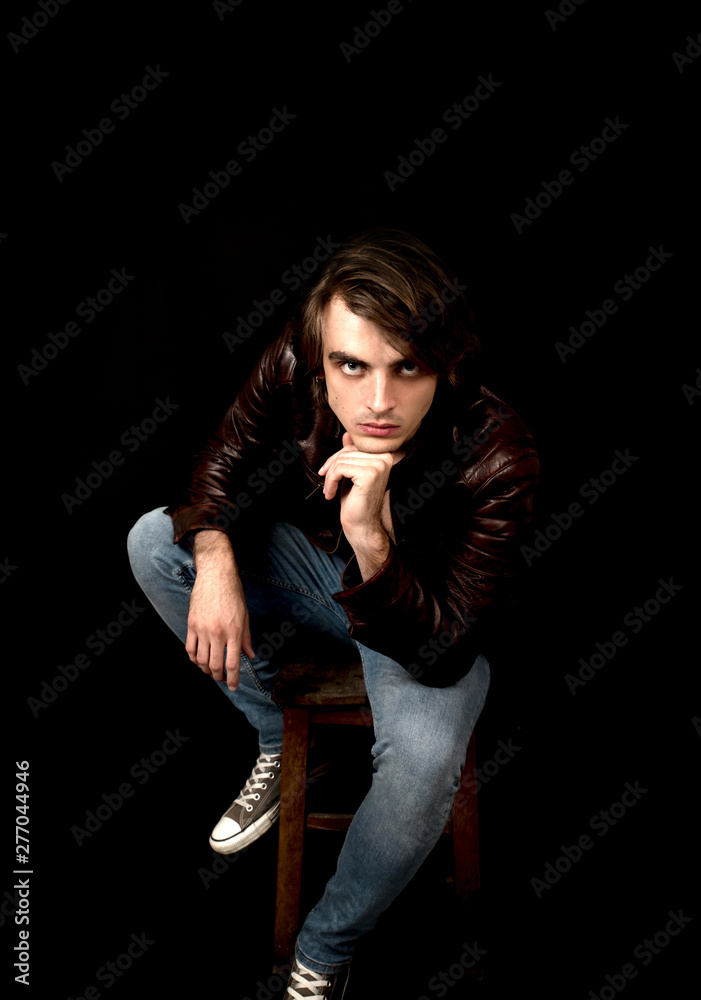 Young man wearing jeans and leather jacket in studio Young man wearing jeans and leather jacket in studio