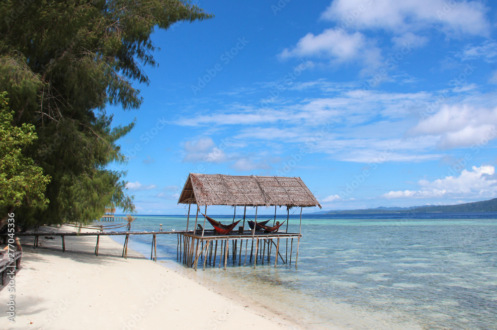 Stilt platform with hammocks over the water on a tropical beach in Raja Ampat on a sunny day. Stilt platform with hammocks over the water on a tropical beach in Raja Ampat on a sunny day.