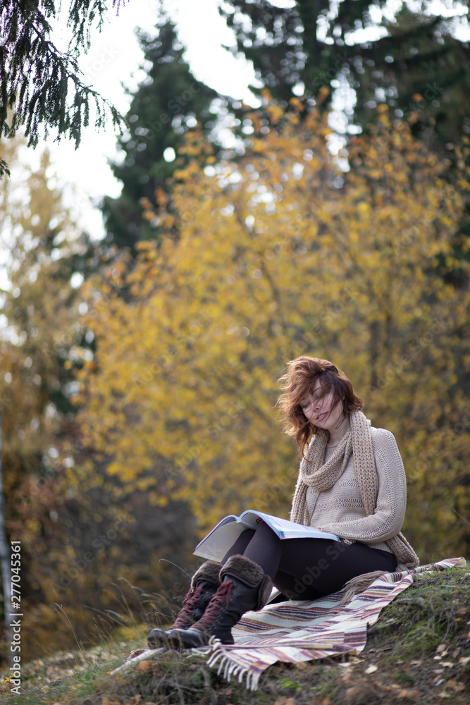 A beautiful brunette girl with curls, autumn in the Park by the water reading a book, clothes beige wool large knit, scarf warm, wind blowing, yellow foliage. A beautiful brunette girl with curls, autumn in the Park by the water reading a book, clothes beige wool large knit, scarf warm, wind blowing, yellow foliage.