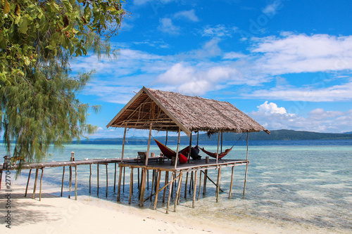 Stilt platform with hammocks over the water on a tropical beach in Raja Ampat on a sunny day.