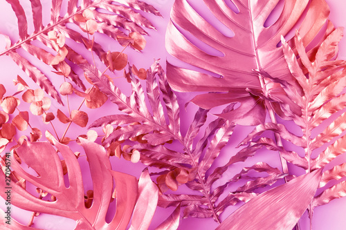 Flat lay of tropical palm leaves in vibrant bold neon holographic colors. Con...