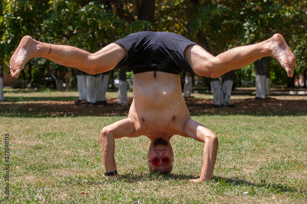 Fototapeta premium A young man doing yoga in the green park. Concept of a healthy lifestyle