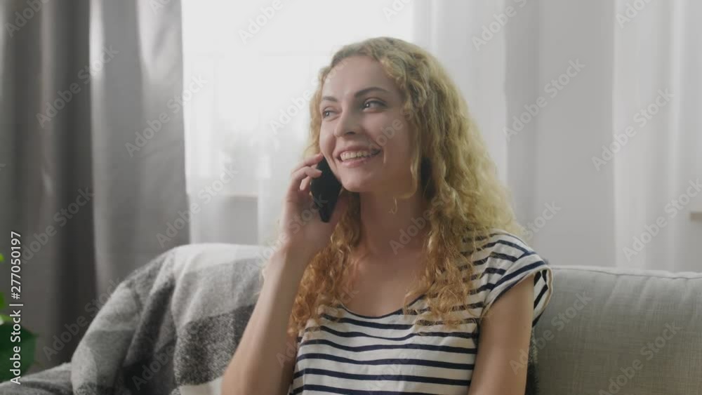 Girl talking on a mobile phone at home on the sofa Girl talking on a mobile phone at home on the sofa