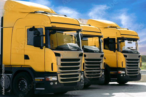 three yellow trucks of a transporting company parked in row in the parking lot. trucking and logistics © producer