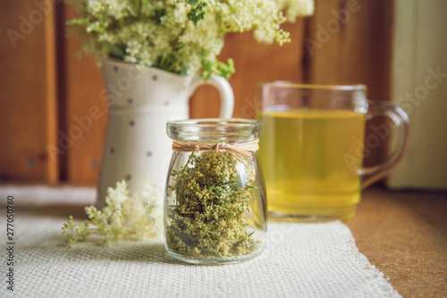 Photos Fresh Meadowsweet, Filipendula ulmaria in jug shape vase and it`s herbal tea in glass, tea powder in jar