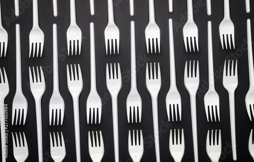 Pattern of white disposable forks on black background, abstraction