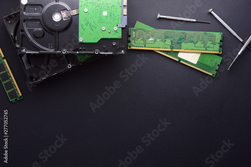 Isolated hard drives, RAM and a set of screwdrivers for computer repair on a black matte background. The concept of data storage and PC repair