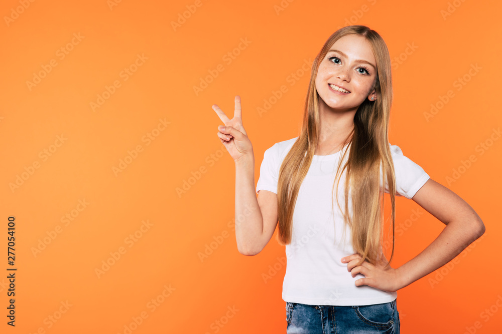 With Victory sigh forever. Beautiful little blonde girl in white t-shirt isolated on colorful background With Victory sigh forever. Beautiful little blonde girl in white t-shirt isolated on colorful background