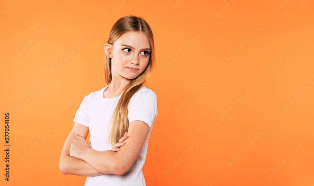 Obraz premium Little cute blonde girl with crossed arms looks away isolated on yellow background.
