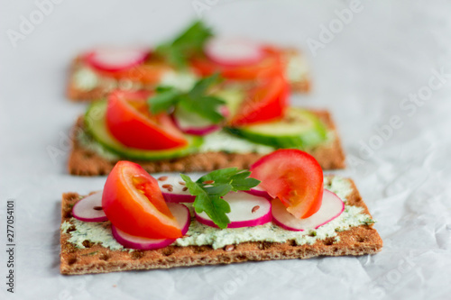 Delicious diet sandwiches with cottage cheese with herbs and vegetables on a white background