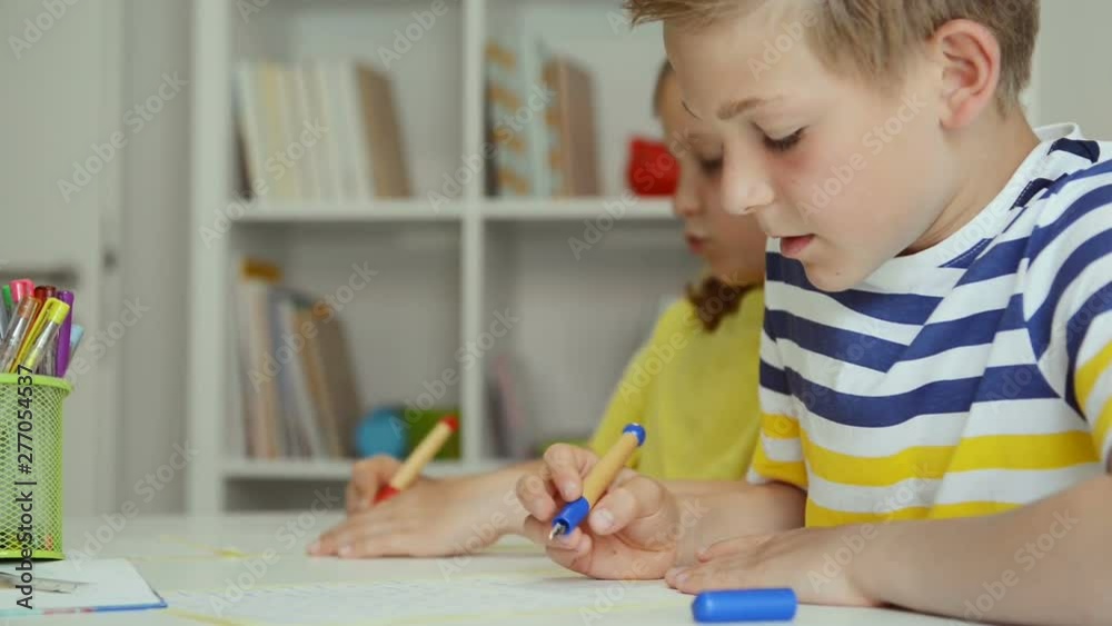 Two cute schoolchildren boy and girl doing homework together at home Two cute schoolchildren boy and girl doing homework together at home