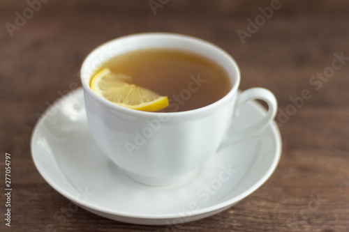 a Cup of herbal tea with a slice of lemon on a wooden background