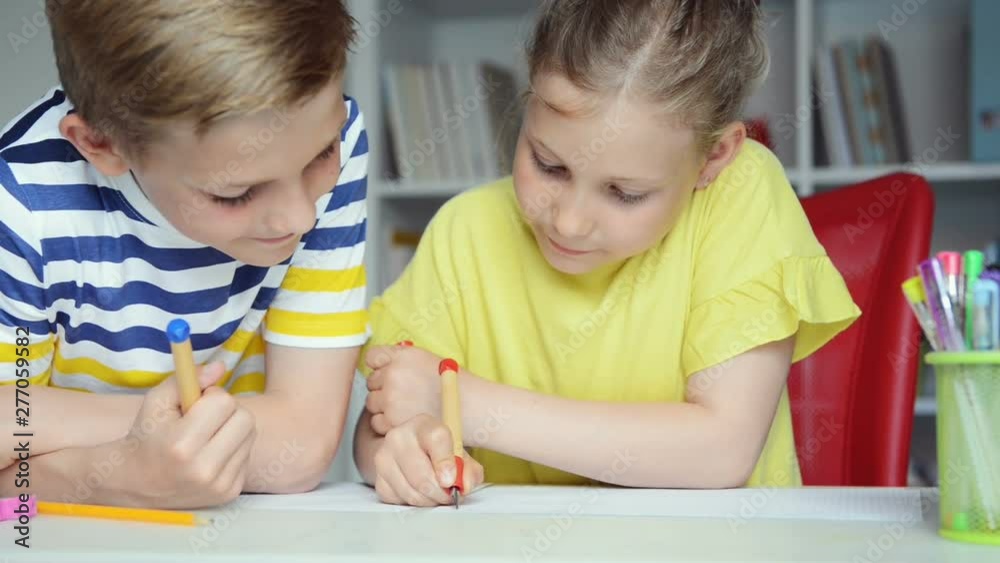Two cute schoolchildren boy and girl doing homework together at home Two cute schoolchildren boy and girl doing homework together at home