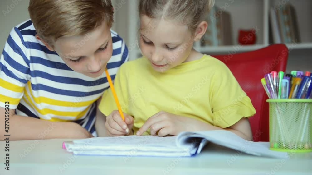 Two cute schoolchildren boy and girl doing homework together at home Two cute schoolchildren boy and girl doing homework together at home