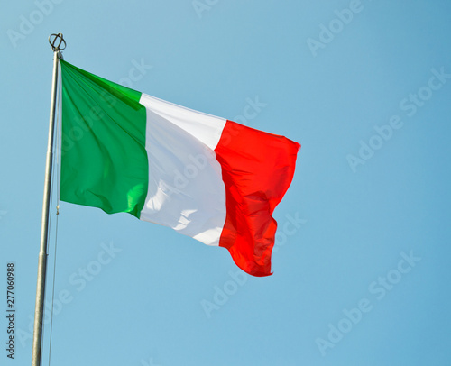 Italian national flag vawing in the wind with blue sky used as background