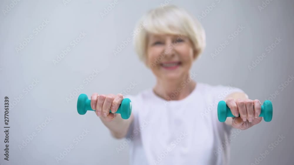 Senior woman with dumbbells smiling at camera, wellness, healthy lifestyle Senior woman with dumbbells smiling at camera, wellness, healthy lifestyle