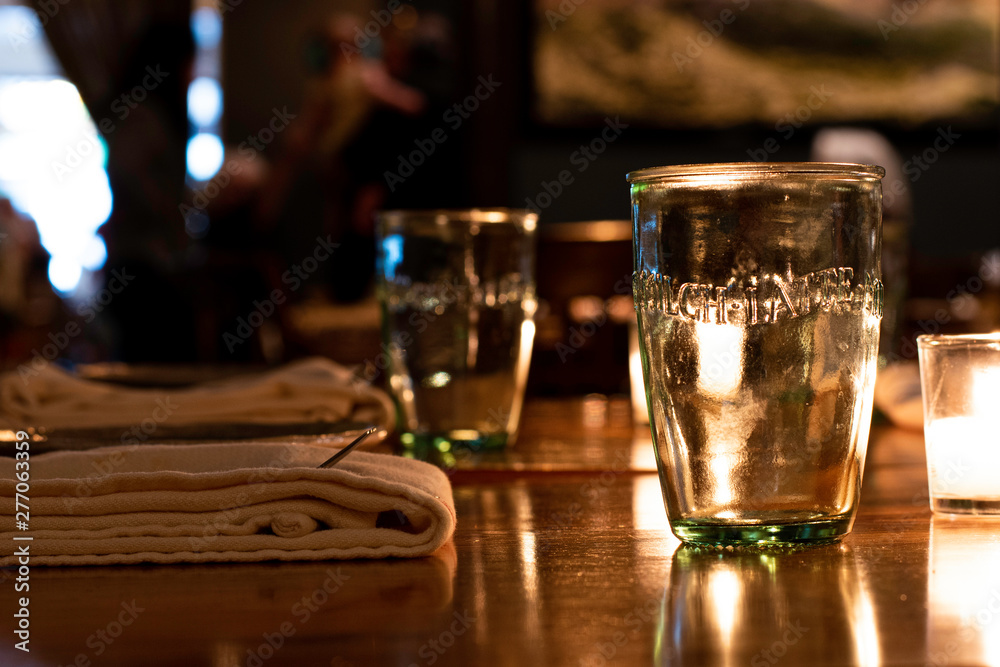 Dark French Bistro Restaurant In Newport, Rhode Island Wooden Table With Candles, Glasses and Place Settings.
