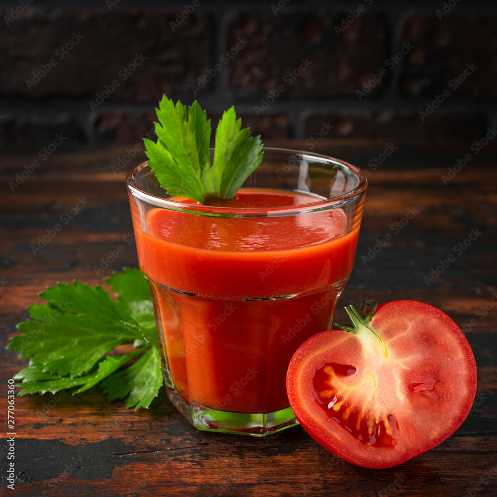 Tomato juice in glass with celery on rustic wooden table Tomato juice in glass with celery on rustic wooden table
