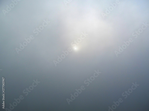 Sun and fog on the sea. View from the deck of a cruise liner at a foggy dawn in the early morning  as a gray background.