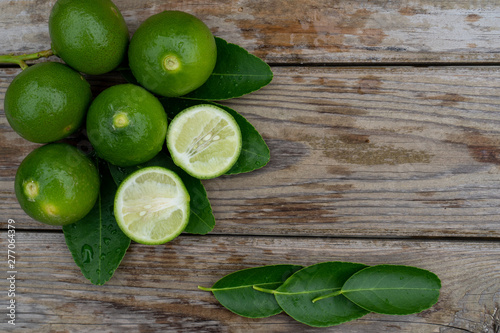 Fresh limes or green lemons on wood table background. Top view with copy space © Panupat