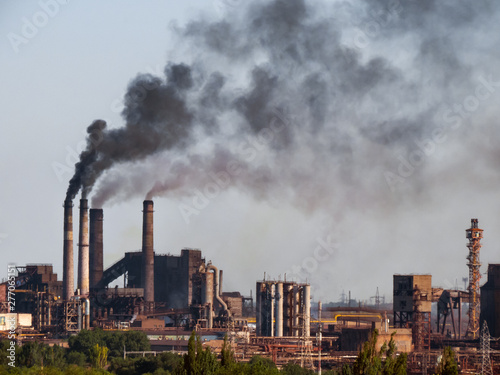 Air pollutants emissions. Toxic smoke of air pollutants, released into the atmosphere by chimney smoking stack at by-product coke plant in metallurgy industry, pollutes the environment. photo